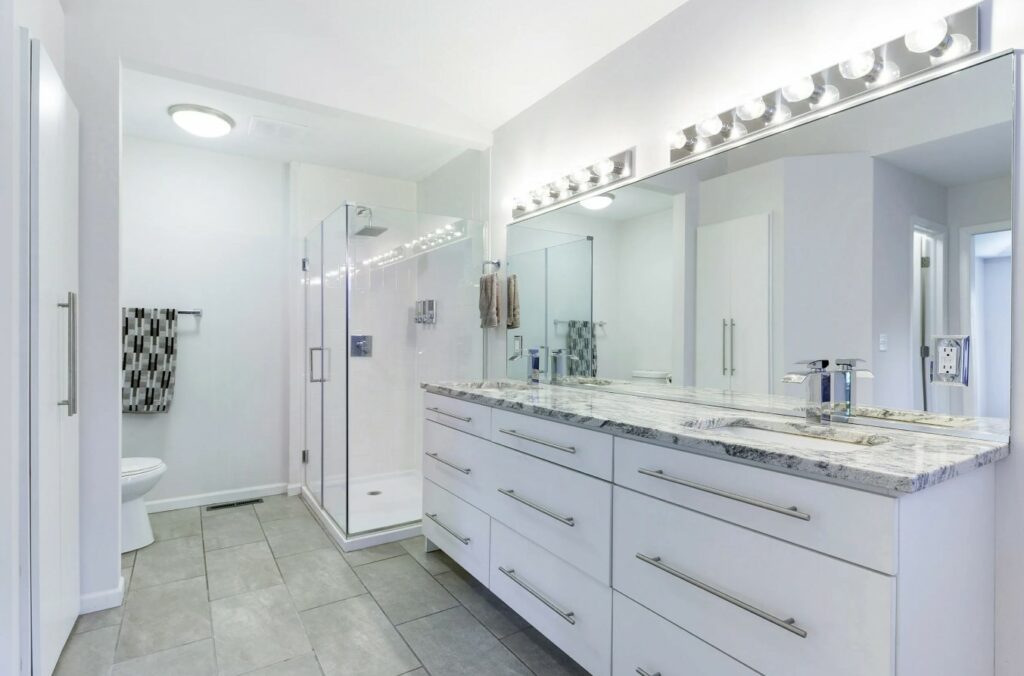 A Pristine Bathroom with White Cabinets and a Spacious Mirror