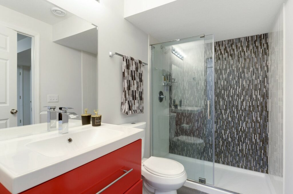 A Bathroom with a Red Cabinet and Glass Shower